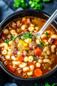 Rustic soup served in a pot, showing elbow macaroni, vegetables, and herbs in a warm tomato base.