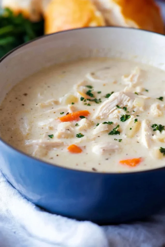 Steaming soup with glossy surface, garnished with fresh herbs for a comforting finish.