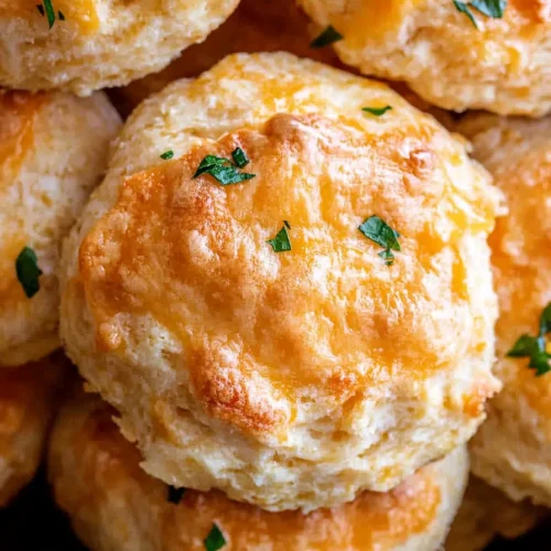 Close-up of flaky, cheesy biscuits with a glossy crust.