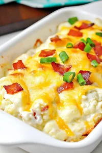 Hearty cauliflower bake layered with melted cheese and garnished with chopped scallions.