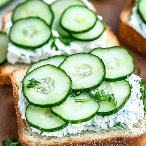 Slices of bread topped with creamy spread and fresh cucumber rounds.