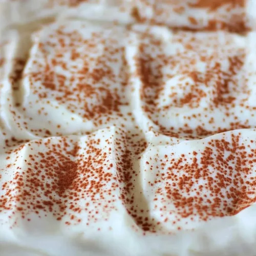 Soft sponge dessert layered with rich cream and cocoa powder sprinkle.