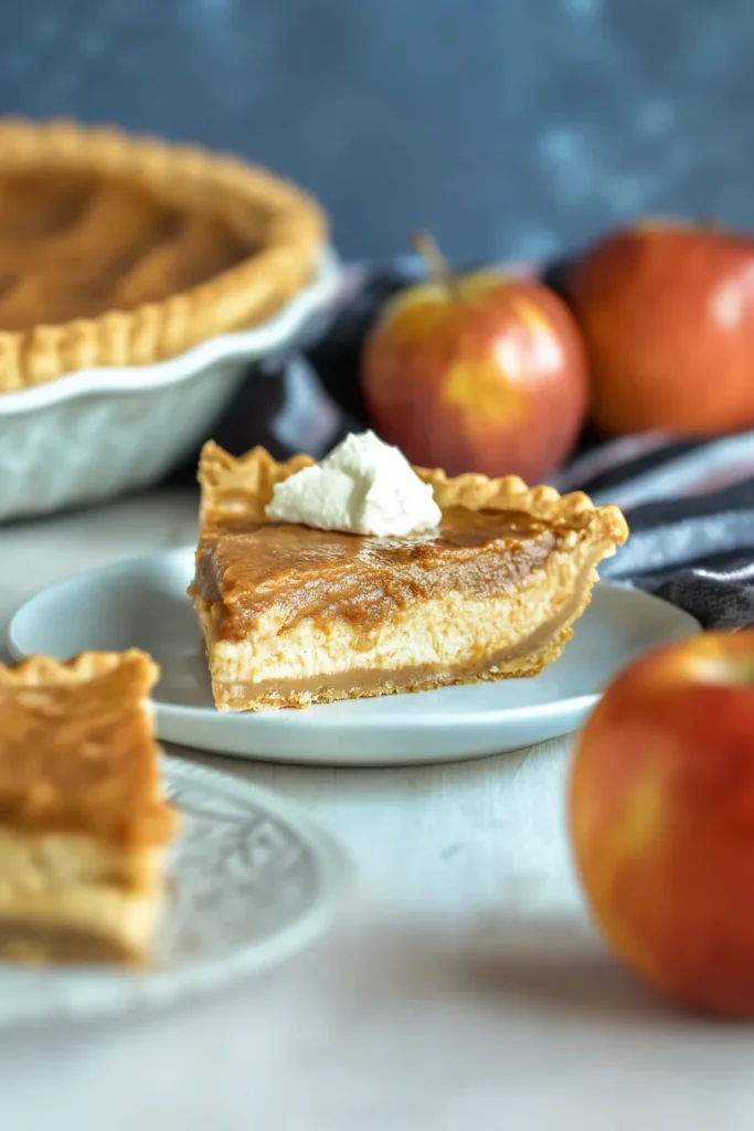 Final shot of apple butter pie served on a dark surface, crust golden and filling glossy.