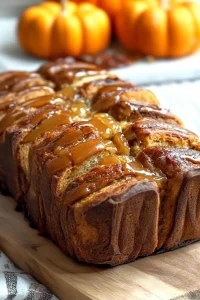 Golden pull-apart bread with glossy cinnamon glaze on a wooden board.