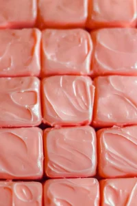 Close-up of creamy pink dessert bars with smooth tops.