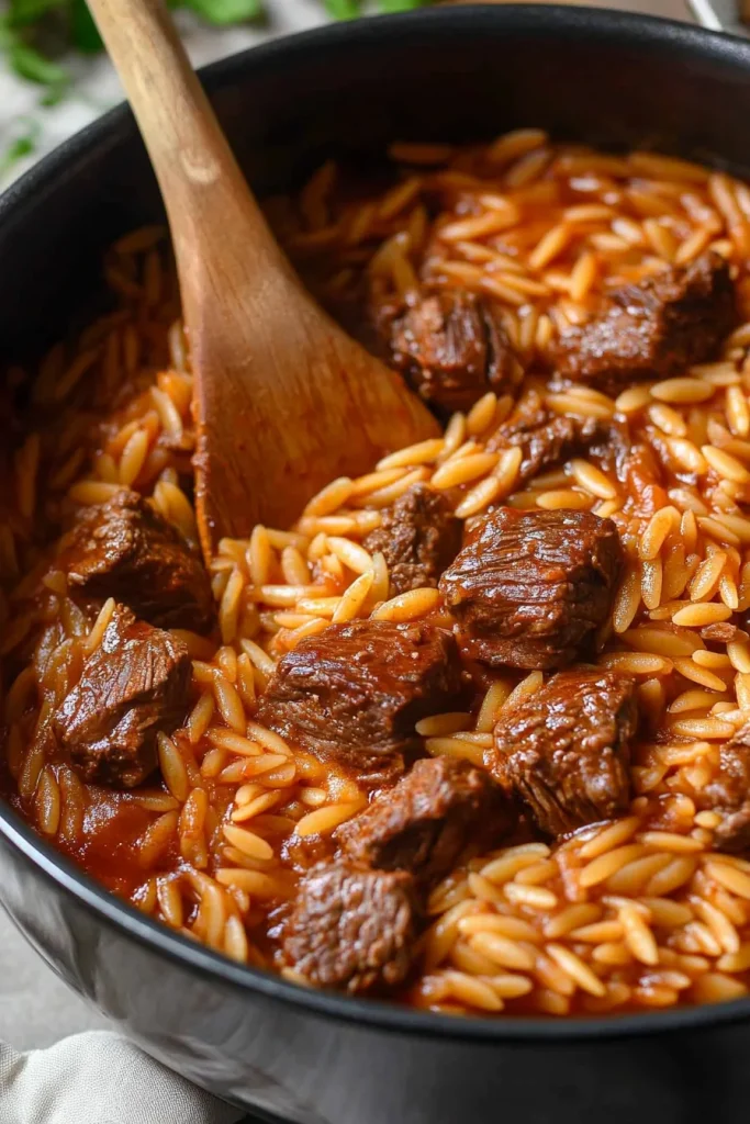 Close-up of braised beef and pasta showing rich color and glossy texture.