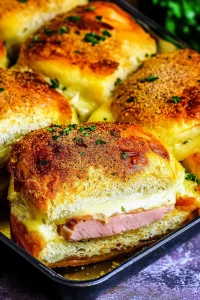 Hearty ham and cheese melt with browned crust and herbs sprinkled around.