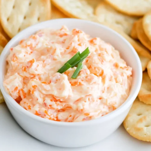 Overhead view of rich, orange spread surrounded by crackers.