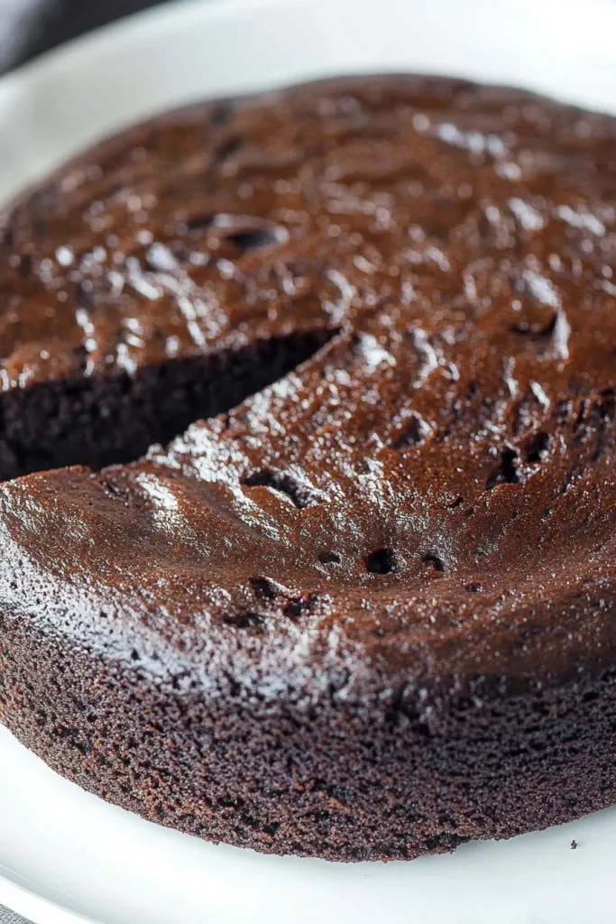 Close-up of a round cake highlighting its deep brown color and smooth finish.