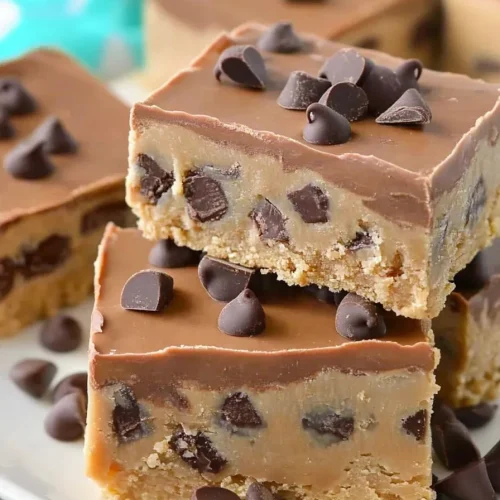 Close-up of rich cookie dough bars drizzled with melted chocolate and scattered chips.