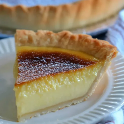 A rustic dessert plate featuring a slice of custard pie, its creamy interior contrasting with the crisp crust.