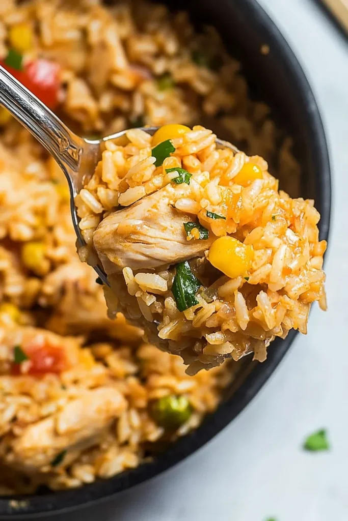 Close-up of seasoned rice with golden chicken chunks and fresh herbs.