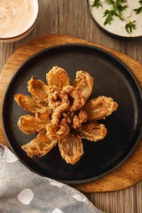 Blooming fried onion presented on a plate, highlighting its crisp layers.