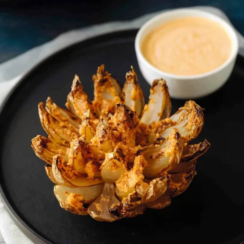 Crispy fried onion petals arranged like a flower, served with dipping sauce.