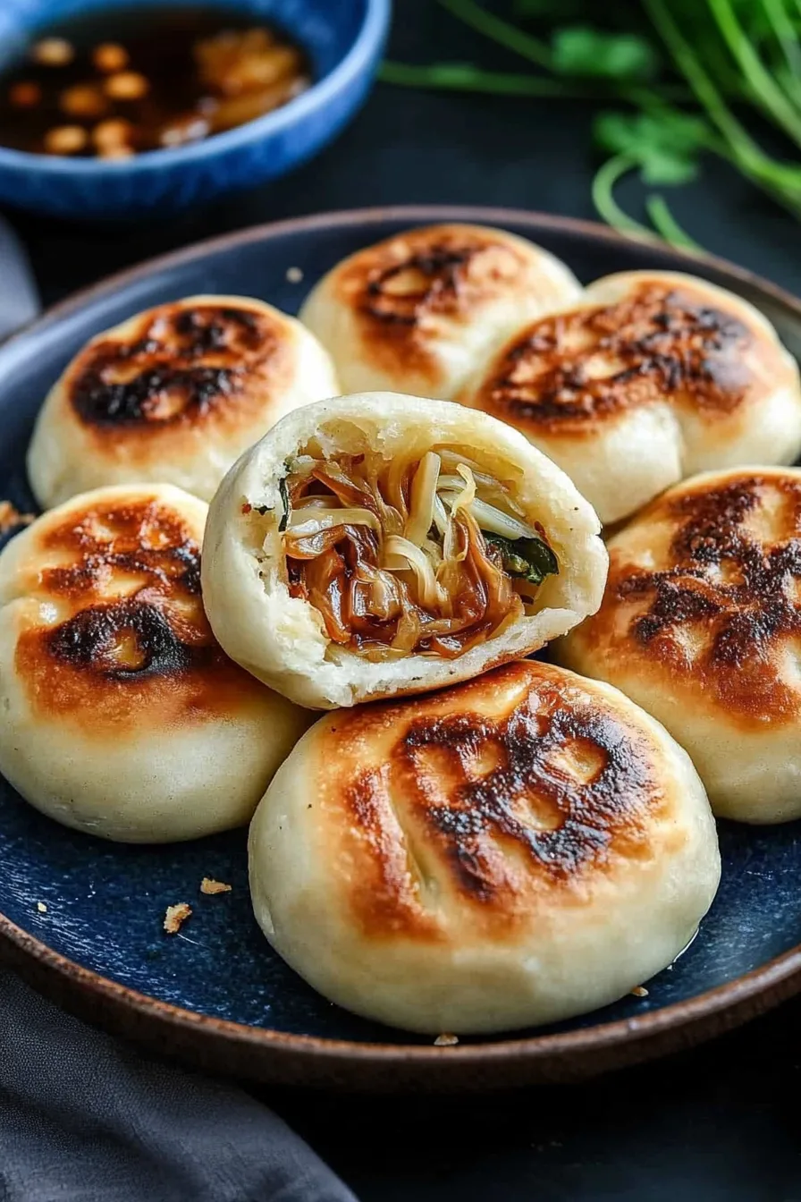 Golden-brown buns with a crispy top, one cut open to reveal noodles and vegetables inside.