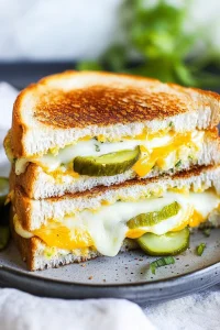 Stacked grilled cheese halves with melted cheese oozing out.