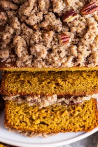 Pumpkin bread loaf highlighting the contrast between soft interior and crisp pecan topping.