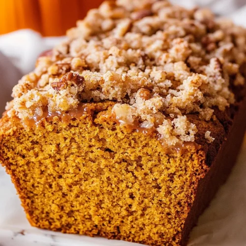 Freshly baked bread with golden streusel topping, presented alongside small seasonal pumpkins.