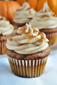 Cupcake with swirled frosting drizzled in caramel sauce.