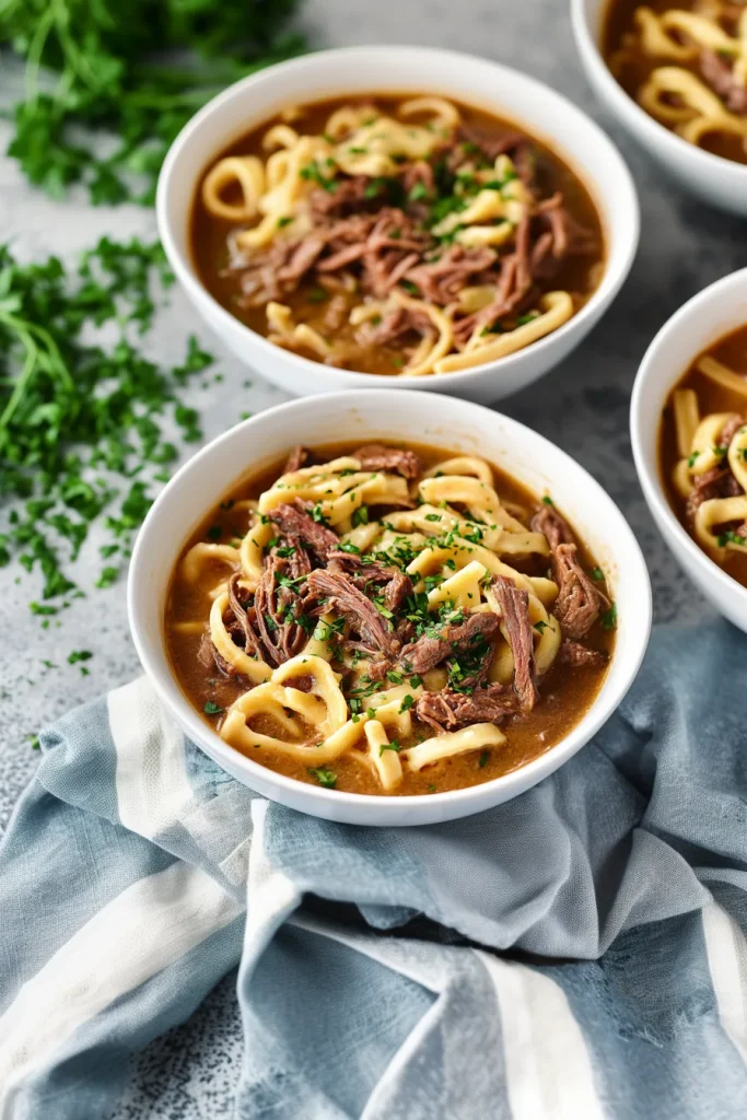 Slow cooker beef and noodles plated with fresh parsley for garnish.
