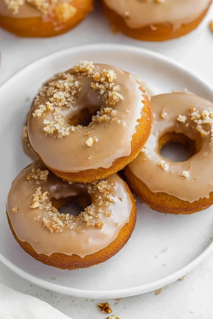 Golden donuts with a glossy glaze arranged neatly on a white plate.