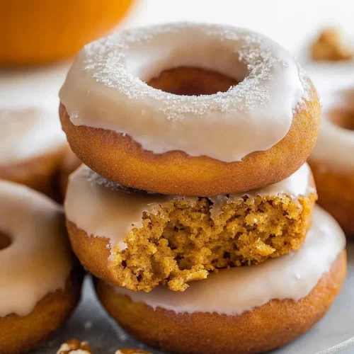 Stack of warm donuts with light crumbs scattered around.