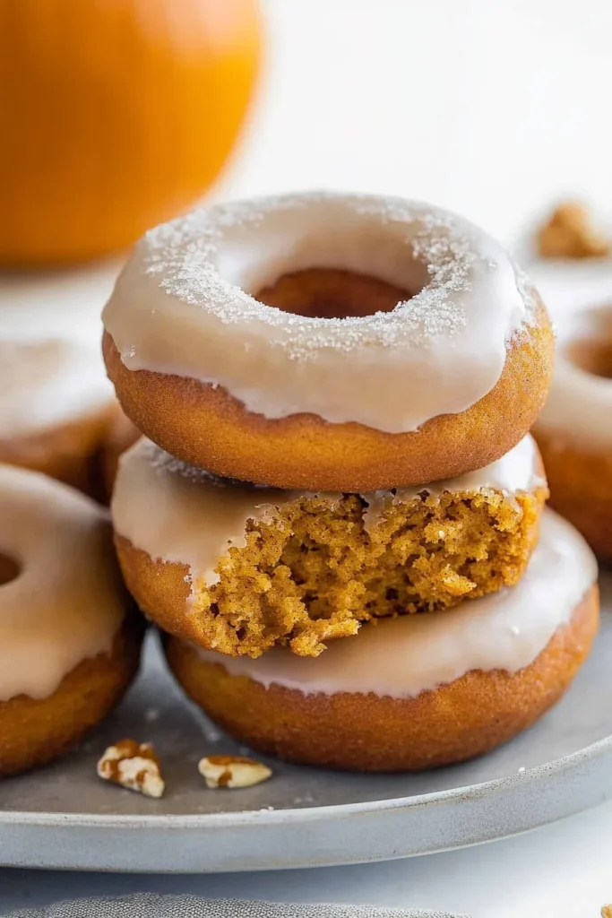 Stack of warm donuts with light crumbs scattered around.