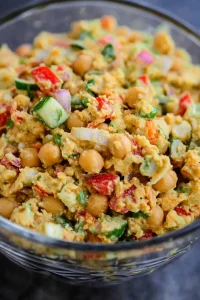 Close-up of colorful chickpea salad highlighting fresh cilantro and diced vegetables.