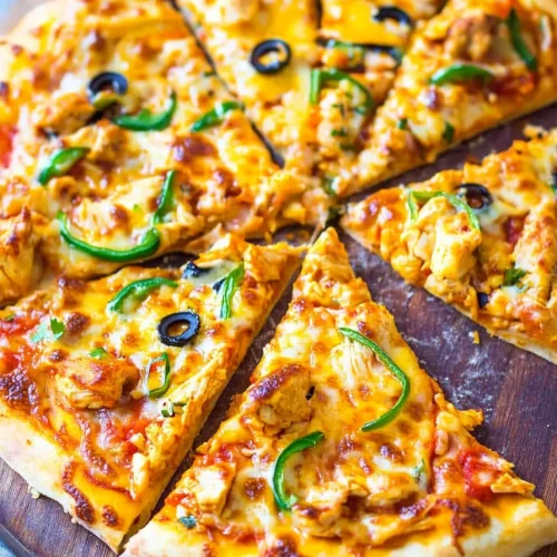 Cheesy pizza topped with chunks of chicken and fresh vegetables.