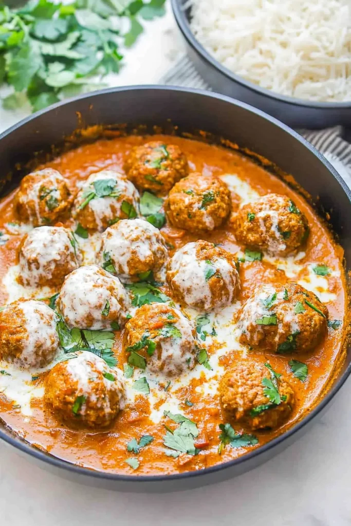 Pan of saucy meatballs served alongside a bowl of white rice