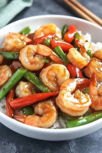Vibrant shrimp dish with red peppers and green peas.