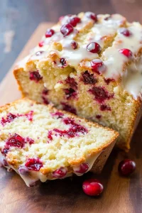 Rustic loaf surrounded by fresh cranberries and halved oranges.