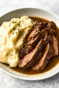 Comfort food presentation showing smooth mashed potatoes and savory meat.
