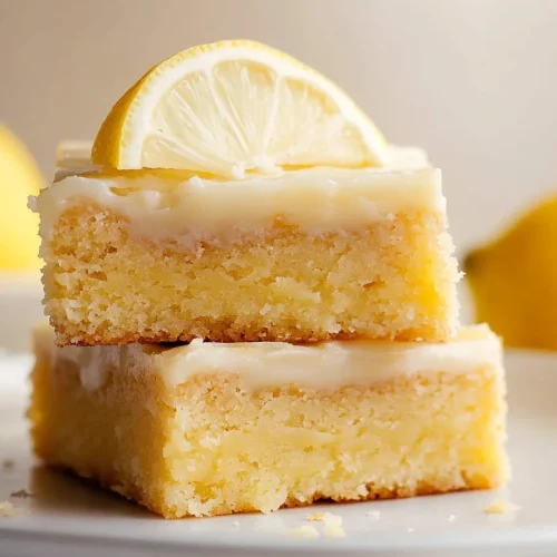Stacked lemon bars showing crumbly crust, soft filling, and citrus garnish
