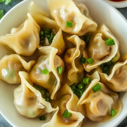Plate of dumplings beside a small bowl of dark soy sauce.